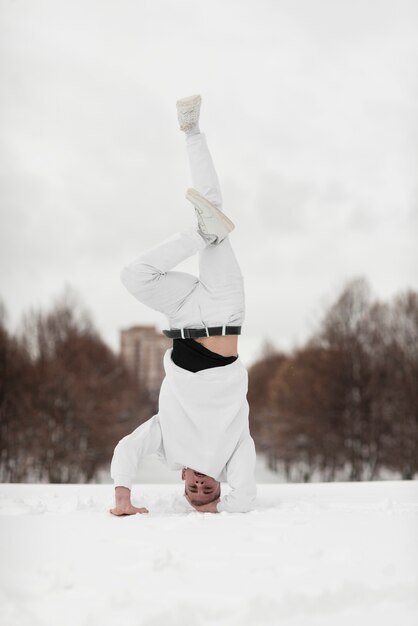 Male hip hop performer standing on head while in the snow