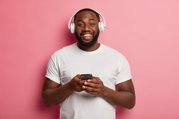 Male hipster listens to music in wireless headphones isolated