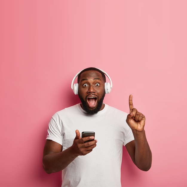 Male hipster listens to music in wireless headphones isolated