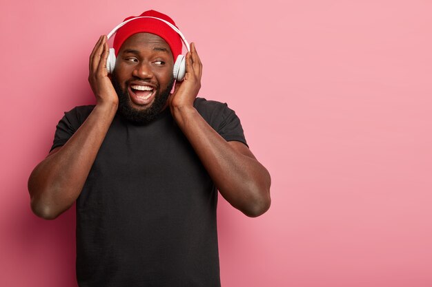 男性のヒップスターは、分離されたワイヤレスヘッドフォンで音楽を聴きます