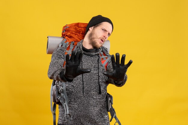 male hitchhiker with leather gloves and backpack making stop sign