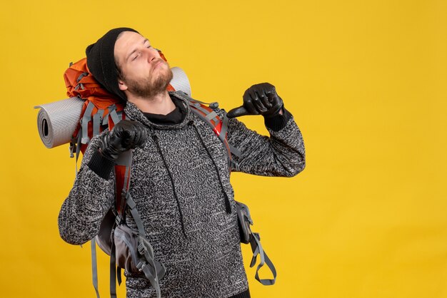 male hitchhiker with leather gloves and backpack pointing fingers himself