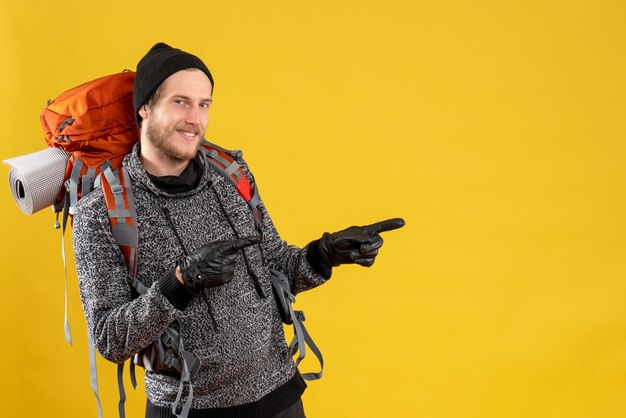 male hitchhiker with leather gloves and backpack pointing fingers right direction