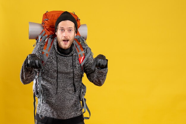 male hitchhiker with leather gloves and backpack pointing at floor