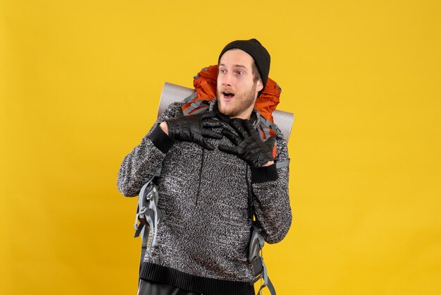 Free photo male hitchhiker with leather gloves and backpack putting hands on his chest