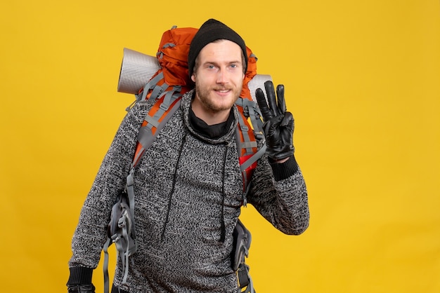 male hitchhiker with leather gloves and backpack showing three fingers