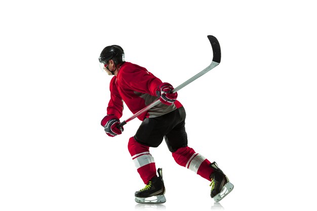 Male hockey player with the stick on ice court and white wall
