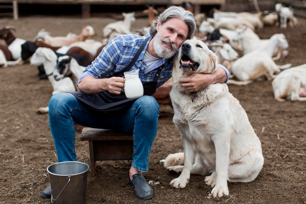 犬と遊んでいる間山羊乳のカップを保持している男性