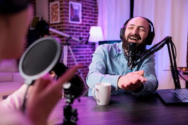 Male influencer having conversation with guest on podcast show, live broadcasting content for social media channel. Young adult interviewing woman about lifestyle entertainment online.