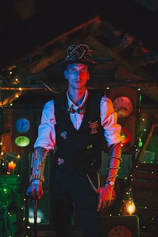 Male inventor in a steampunk suit, top hat, glasses with a cane in his hand in a watch workshop