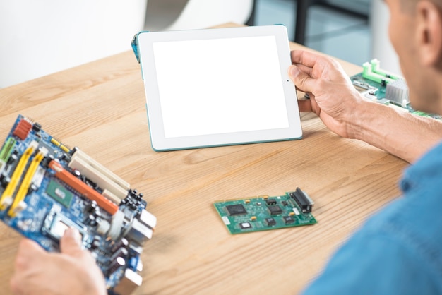 Male IT technician holding digital tablet and motherboard