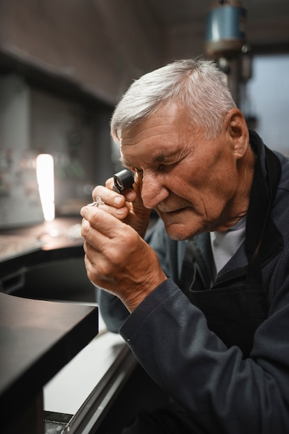 Male jeweler working in the shop with magnifying glass