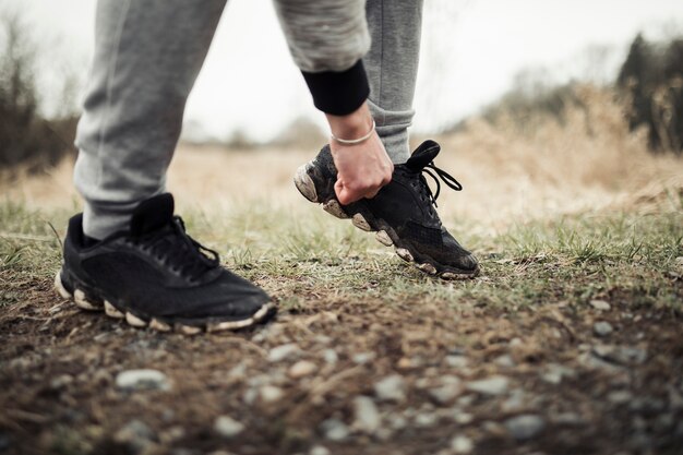 Male jogger standing on trail adjusting his shoe