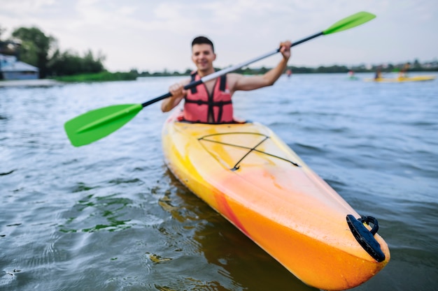 Male kayaker paddling kayak on lake