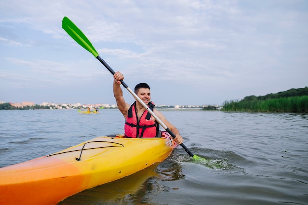 Male kayaker paddling kayak on lake