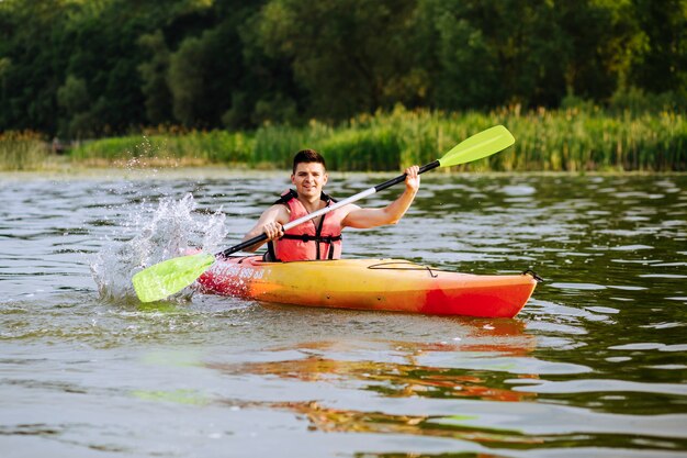 Male kayaker splashing water while kayaking on lake