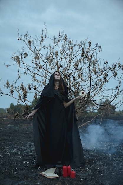 Male mage in black clothes looking away holding a skull