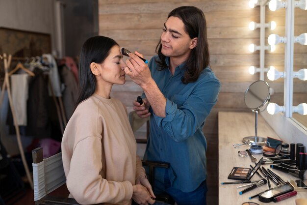 Male make-up artist putting on make-up on female client