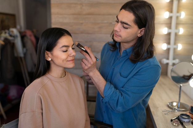 Male make-up artist putting on make-up on female client