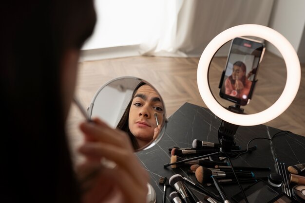 Male make-up artist putting on make-up on himself