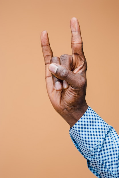 Foto gratuita la mano dell'uomo maschio si è alzata mostrando un segno della roccia di metalli pesanti, gesto delle corna