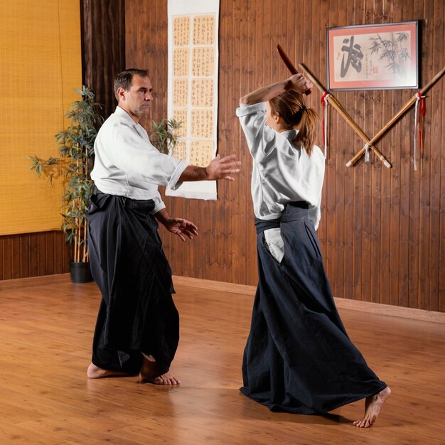 男性の武道インストラクターが女性の研修生と一緒に練習場でトレーニング
