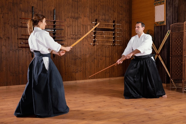 若い女性の訓練生と一緒に練習場で訓練する男性の武道のインストラクター