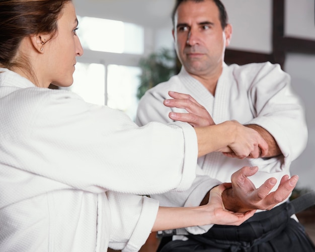 Male martial arts instructor training with female trainee in practice hall