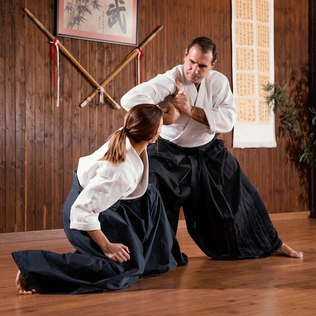 Free photo male martial arts instructor training with trainee in practice hall