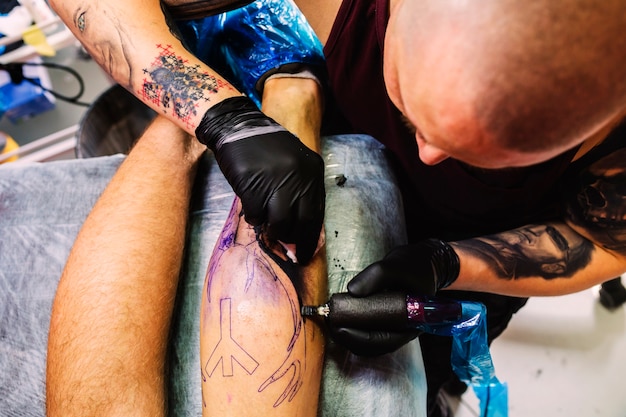 Male master doing tattoo on leg