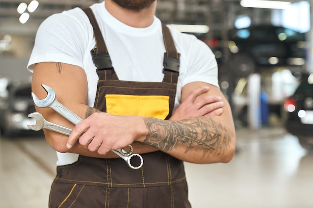 Free photo male mechanic with muscular hands and tattoo keeping wrench