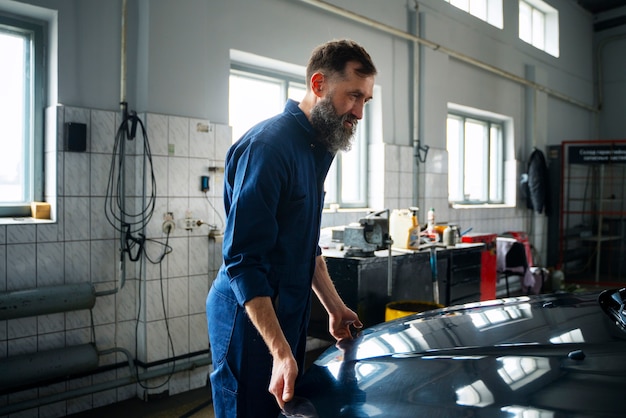 Foto gratuita meccanico maschio che lavora nell'officina riparazioni auto sull'automobile