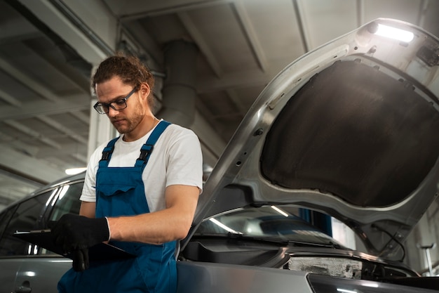 Free photo male mechanic working in the shop on a car