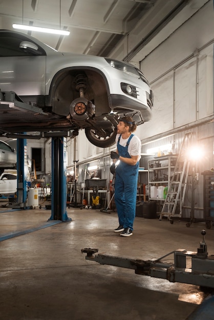 Free photo male mechanic working in the shop on a car