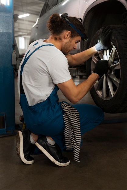 Free photo male mechanic working in the shop on a car