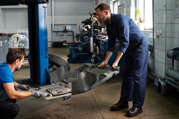 Foto gratuita meccanici maschi che lavorano insieme all'auto nel negozio