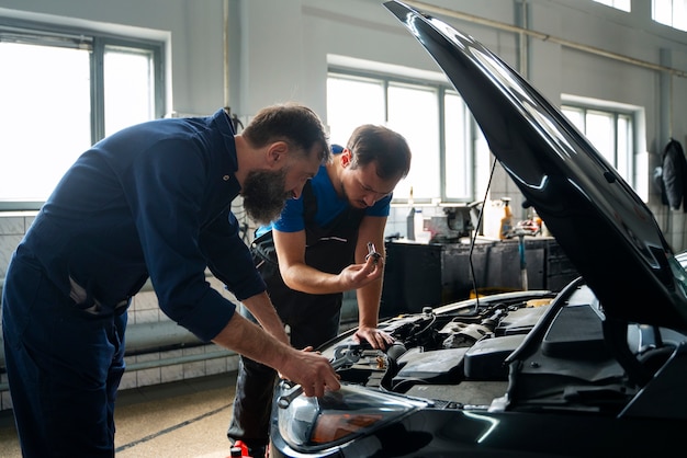 Meccanici maschi che lavorano insieme sull'auto nel negozio