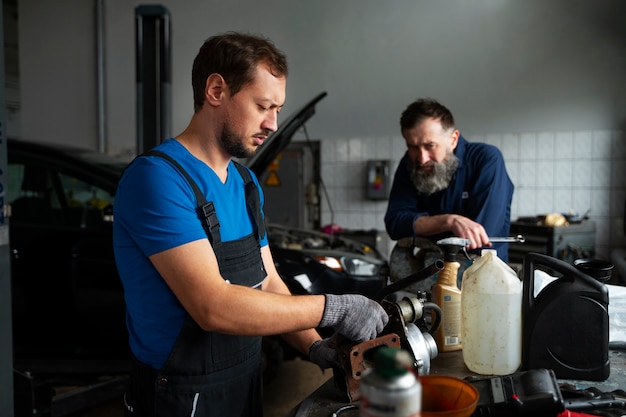 Free photo male mechanics working together on car in the shop