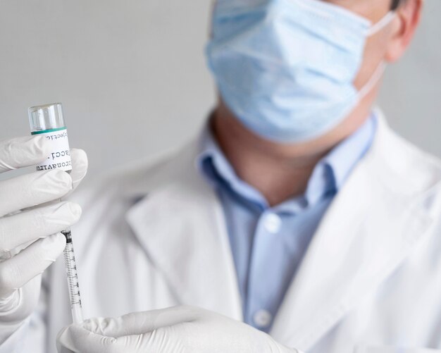 Male medic holding vaccine vial with syringe