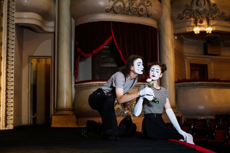 Free Photo male mime artist giving white rose to female mime sitting on stage