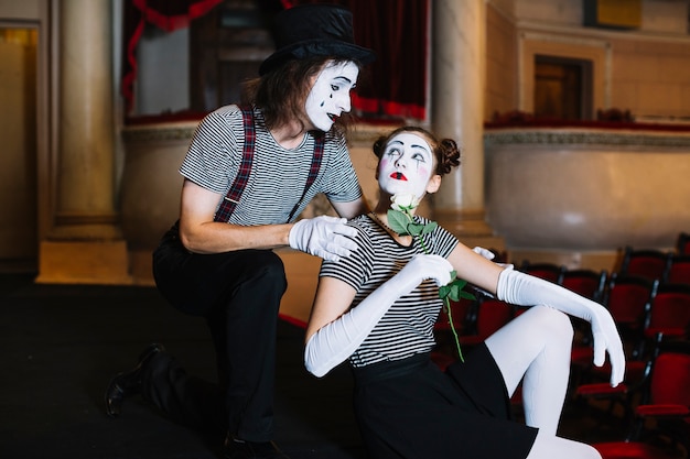 Free photo male mime artist looking at female mime holding white rose