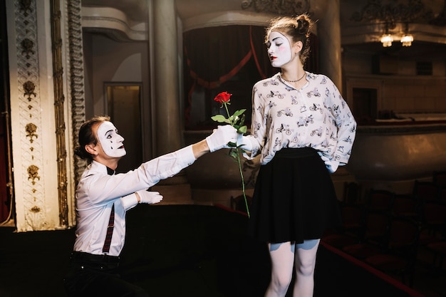 Male mime giving red rose to female mime artist on stage