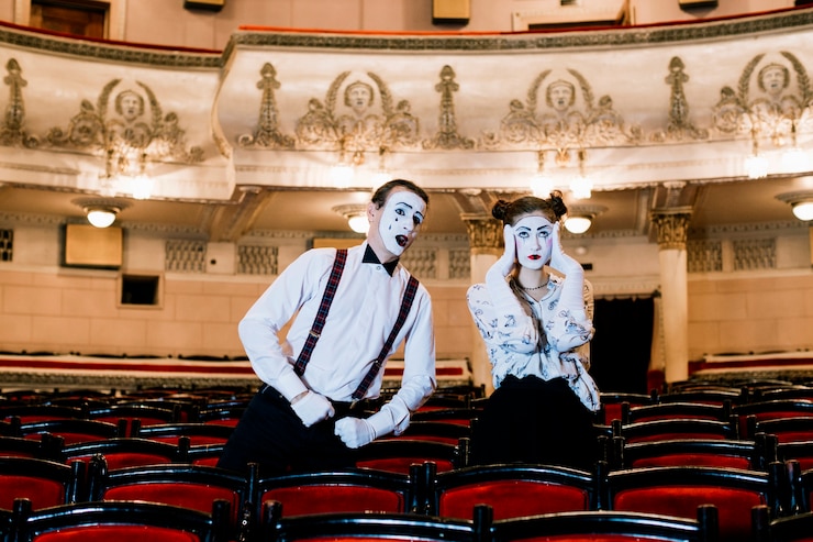Free Photo male mime posing near the sad female mime sitting on chair