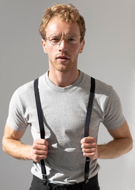 Free photo male model holding his suspenders front view