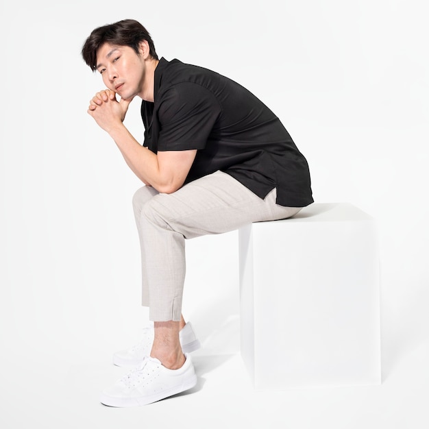 Male model posing and sitting on a chair in minimal outfit full body