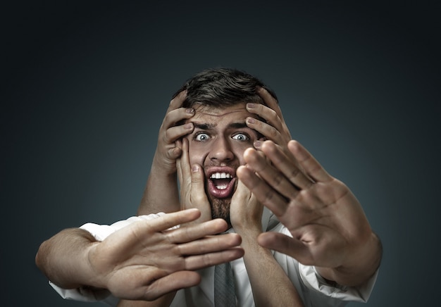 A male model surrounded by hands like his own thoughts on dark wall