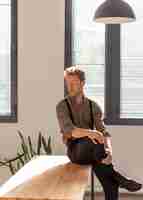 Free photo male model with curly hair sitting on the table