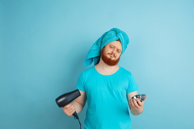 Male model with natural red hair blowing dry his beard, making up hairstyle