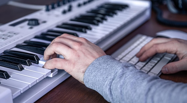 남성 음악가는 컴퓨터와 키보드 음악가 작업 공간을 사용하여 음악을 만듭니다.