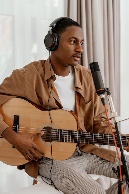 Foto gratuita musicista maschio a casa con cuffie e chitarra